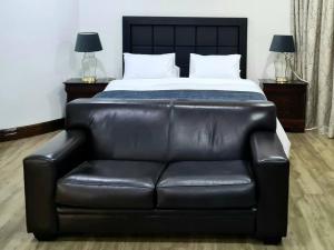 a black leather couch in a bedroom with a bed at Spacious Golf & Wildlife Estate in Hartbeespoort 10 sleeper in Hartbeespoort