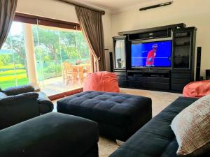 a living room with couches and a tv in a room at Spacious Golf & Wildlife Estate in Hartbeespoort 10 sleeper in Hartbeespoort