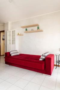 Forum Assago appartamento في أسّاغو: أريكة حمراء في غرفة معيشة مع طاولة