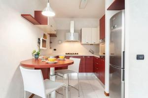 uma pequena cozinha com uma mesa de madeira e cadeiras brancas em Forum Assago appartamento em Assago