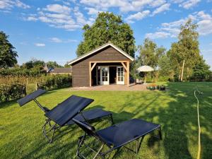 una casa con 2 sillas y una cabaña en De WiedenWeide en Wanneperveen