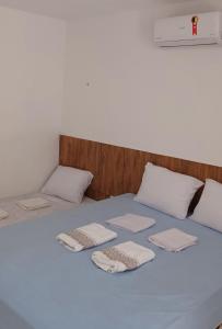 Una cama con toallas blancas encima. en Pousada Bom gosto, en São Miguel do Gostoso