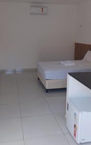 Habitación blanca con cama y nevera. en Pousada Bom gosto, en São Miguel do Gostoso