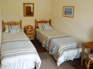 two beds in a small room with a mirror at Penfound Country Cottage in Poundstock