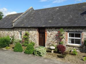 a stone house with flowers in front of it at Penfound Country Cottage in Poundstock
