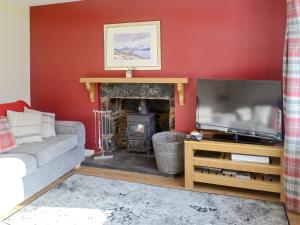 a living room with a fireplace and a television at Elmbank in Lochcarron