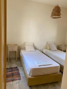 two beds in a room with two tables at Nefeli Residence @ Astypalaia island in Analipsi