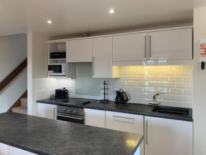 a kitchen with white cabinets and a black counter top at Mill House in North Somercotes