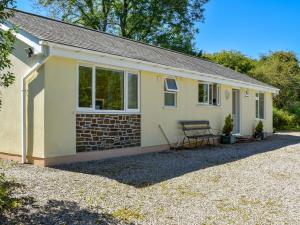 una casa amarilla con un banco delante en Green Valley Retreat en Holsworthy