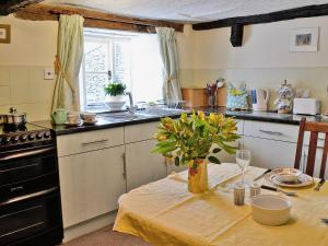 a kitchen with a table with a vase of flowers on it at Barker Knott Farm Cottage in Bowness-on-Windermere