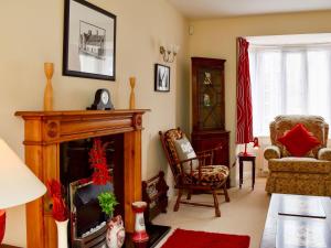 a living room with a fireplace and a chair at Red Lion Cottage in Chatteris