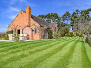 een groot grasveld voor een stenen huis bij The Warren in Wellesbourne Hastings