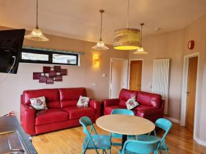 a living room with a red couch and a table at Tor Farm Lodge in Cheddar