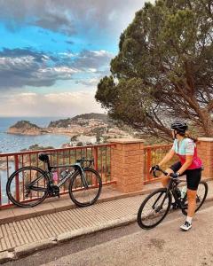 a woman riding a bike on a bridge near the ocean at Josep Mº Folch Centro in Tossa de Mar