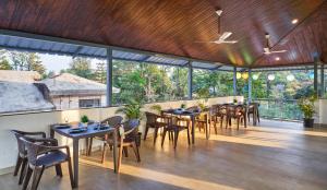 馬哈巴萊斯赫瓦爾的住宿－Drizzle Resort Mahabaleshwar，用餐室设有桌椅和窗户。