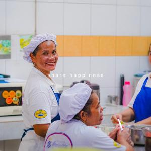 une femme debout dans une cuisine avec une autre femme dans l'établissement Hotel Deli River and Restaurant Omlandia, à Medan