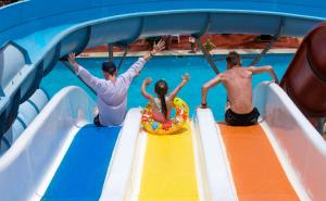 Tres personas en un tobogán de agua en una piscina en Mirage Bay Resort & Aqua Park, en Hurghada