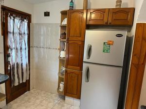 cocina con nevera blanca y armarios de madera en Barrio Country en Piriápolis