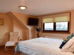 a bedroom with a bed and a tv and a chair at Bankhead Farm Cottage in Crossgates