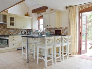 a kitchen with white cabinets and a island with stools at Goose Cottage - Ukc2676 in Poundstock