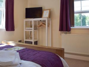1 dormitorio con 1 cama con sábanas moradas y TV en Conway Cottage en Pembroke