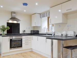 a kitchen with white cabinets and a black counter top at No, 1 Ash Cottage in Quatt