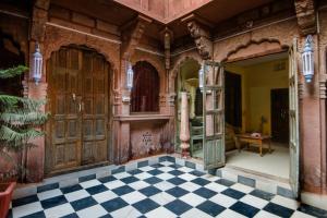 una casa antigua con suelo a cuadros y grandes puertas de madera en Heritage Gouri Haveli, en Jodhpur
