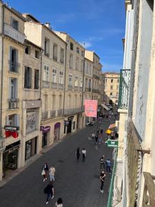een groep mensen die door een straat met gebouwen lopen bij La Comédie, appart de Charme in Montpellier