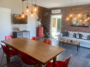 uma sala de estar com uma mesa de madeira e cadeiras vermelhas em Chez Mimi em Saint-Germain-sur-Ay