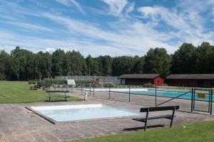 a swimming pool with two benches next to it at Cosy cabin w fireplace 3 mins from Söderåsen Park in Ljungbyhed