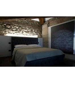1 dormitorio con 1 cama grande y pared de piedra en ATTIKO 53 Boutique Rooms, en Verona