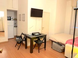 Kleines Zimmer mit einem Schreibtisch und einem Bett sowie einem Tisch und Stühlen. in der Unterkunft Porta Venezia Flat in Mailand