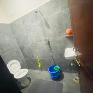 baño con aseo y cubo de basura azul en Dharani Home Stay, en Badami