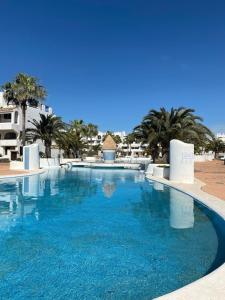 ein großer blauer Pool mit Palmen und Gebäuden in der Unterkunft Marina Dor II - Cala Egos- Sunny ground floor apartment with large garden in Portopetro