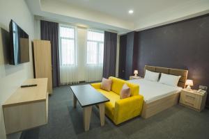 um quarto de hotel com uma cama e um sofá amarelo em Ogguesto Hotel em Baku