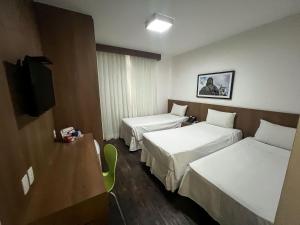 a hotel room with two beds and a television at Nobile Hotel Belo Horizonte in Belo Horizonte