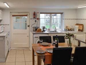 a kitchen with a wooden table and a dining room at Glen Cottage in Yaxham