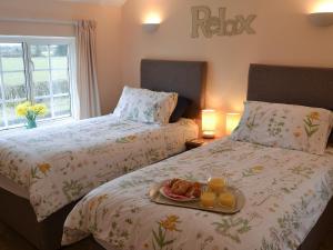 a bedroom with two beds with a tray of food at Glen Cottage in Yaxham