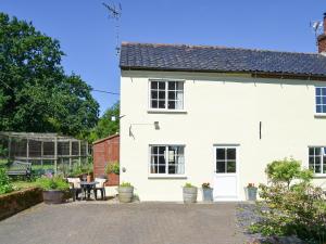 a white house with a patio and a garden at Glen Cottage in Yaxham