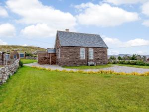 an old stone house with a grass yard at The Old School House in Oldshore