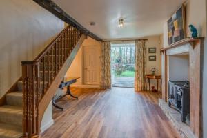 a living room with a staircase and a fireplace at Woodmancote Manor Cottage in Cirencester