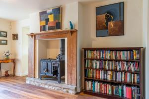 Woodmancote Manor Cottage في سيرنسيستر: غرفة معيشة مع موقد ورف للكتب مليئ بالكتب