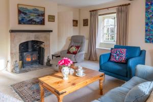 a living room with a table and a fireplace at Woodmancote Manor Cottage in Cirencester