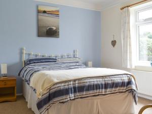 a bedroom with a bed with blue walls and a window at Longstone in Poundstock