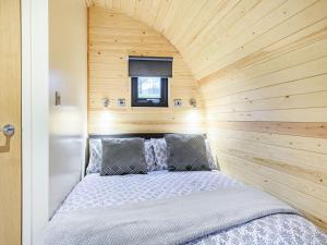 Łóżko w niewielkim pokoju z drewnianą ścianą w obiekcie Holdenby - Ukc5323 w mieście East Haddon