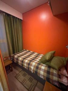 a small bedroom with a bed with an orange wall at Outapailakka K19 in Saariselka