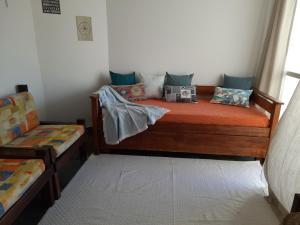 um quarto com uma cama de madeira e almofadas em Jardim Tropical em Lauro de Freitas