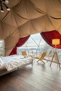 a bedroom with a bed and chairs and a large window at Villas Fomich in Bukovel