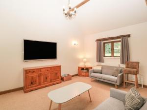 a living room with a tv and a couch at Honeysuckle Cottage in Worcester