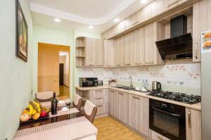 - une cuisine avec des placards en bois et une table avec des fruits dans l'établissement Rustaveli Three Bedroom Apartment with Amazing views, à Tbilissi